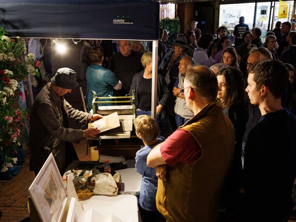 Druck-Vorführung einer Radierung vor dem Kulturhaus.