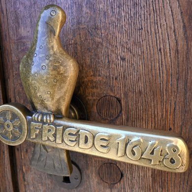 Die Tür zum Rathaus ziert eine Friedenstaube und das Jahr des Friedensschlusses 1648.