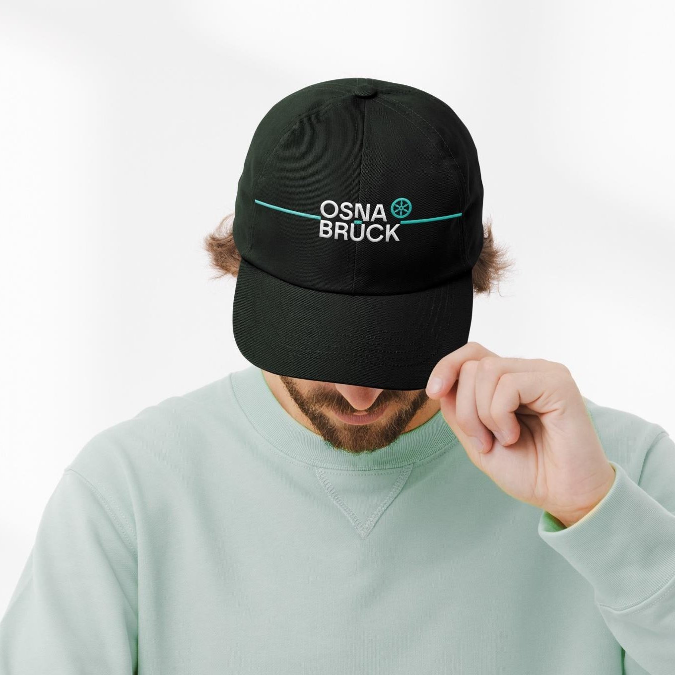 Person trägt schwarze Basecap mit Stadtlogo.